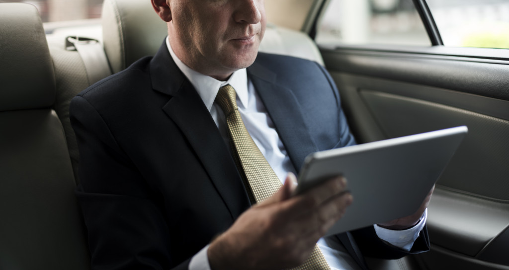 businessman using his tablet inside his car