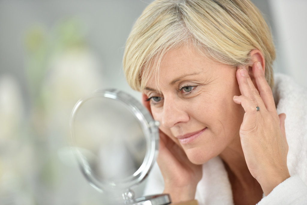 woman inspecting her face for signs of ageing in a mirror