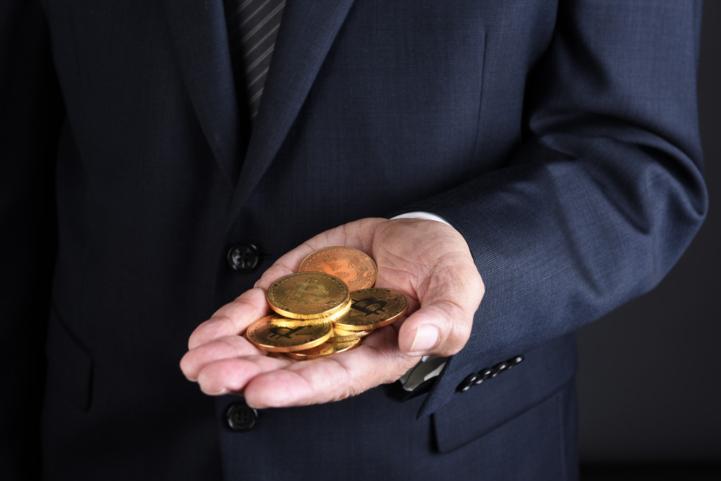 Closeup of a businessman holding several BitCoin crypto currency coins in his hand.