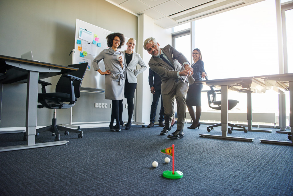 A group of business professionals playing mini golf inside the office