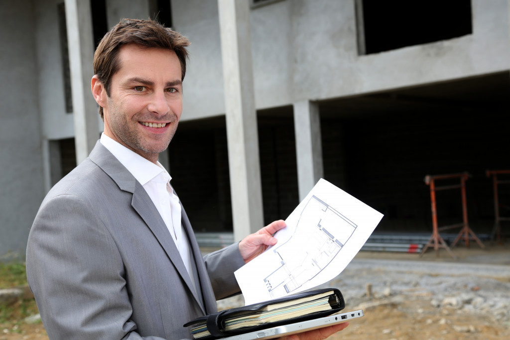 a man holding a blueprint of an ongoing real estate