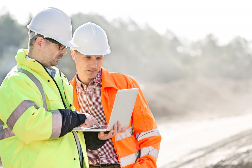 two men discussing something on the laptop in a construction site