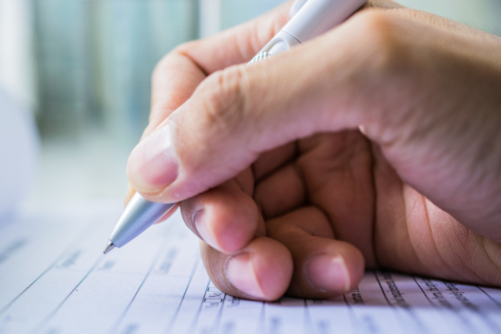 A hand holding a pen about to sign a document