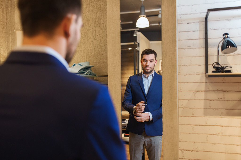 male businessman wearing a formal suit in front of mirror