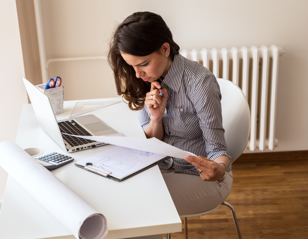 female business owner checking documents in front of laptop