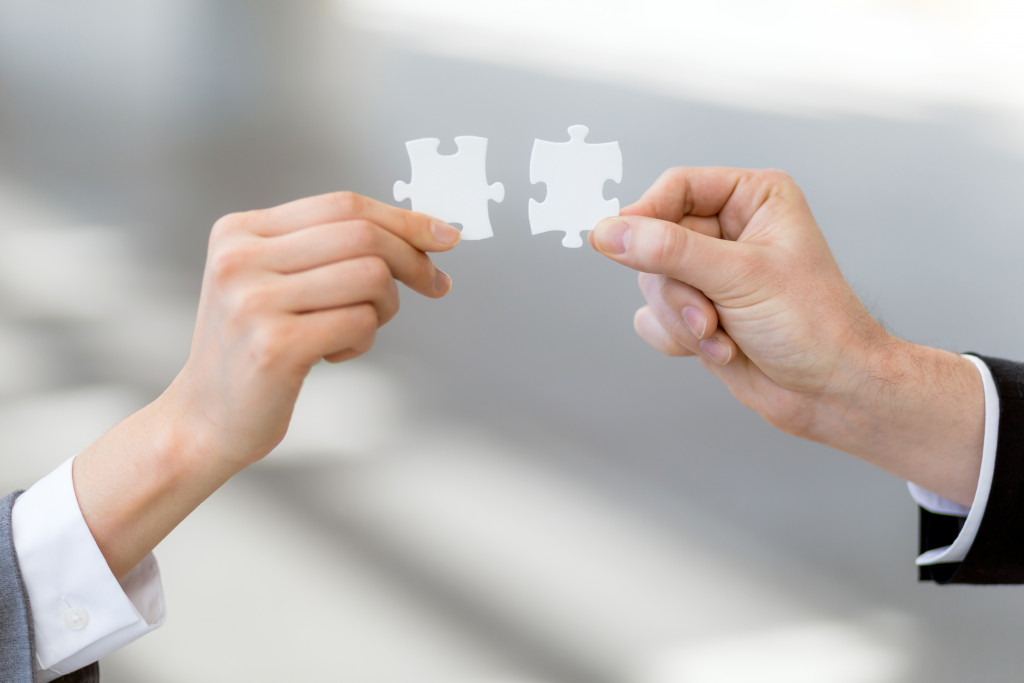 man and woman business owners holding puzzle pieces that go together to represent marriage