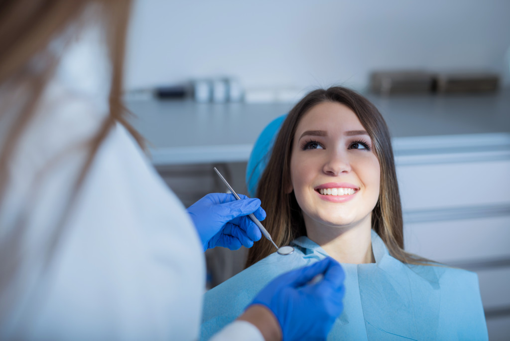 woman smiling at female dentist about to check her teeth