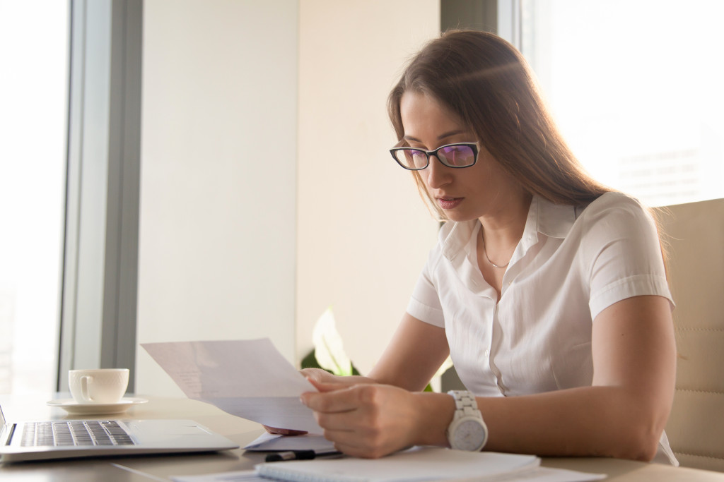 A businesswoman analyzing a document in front of a laptop