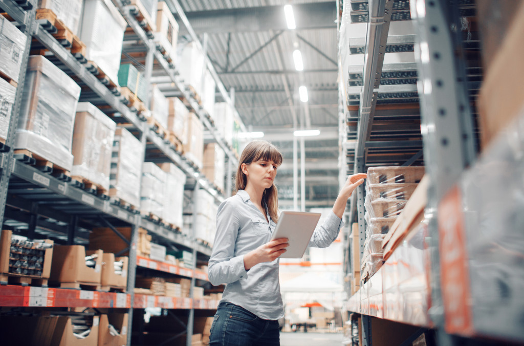 female employee checking boxes in warehouse using tablet in hand