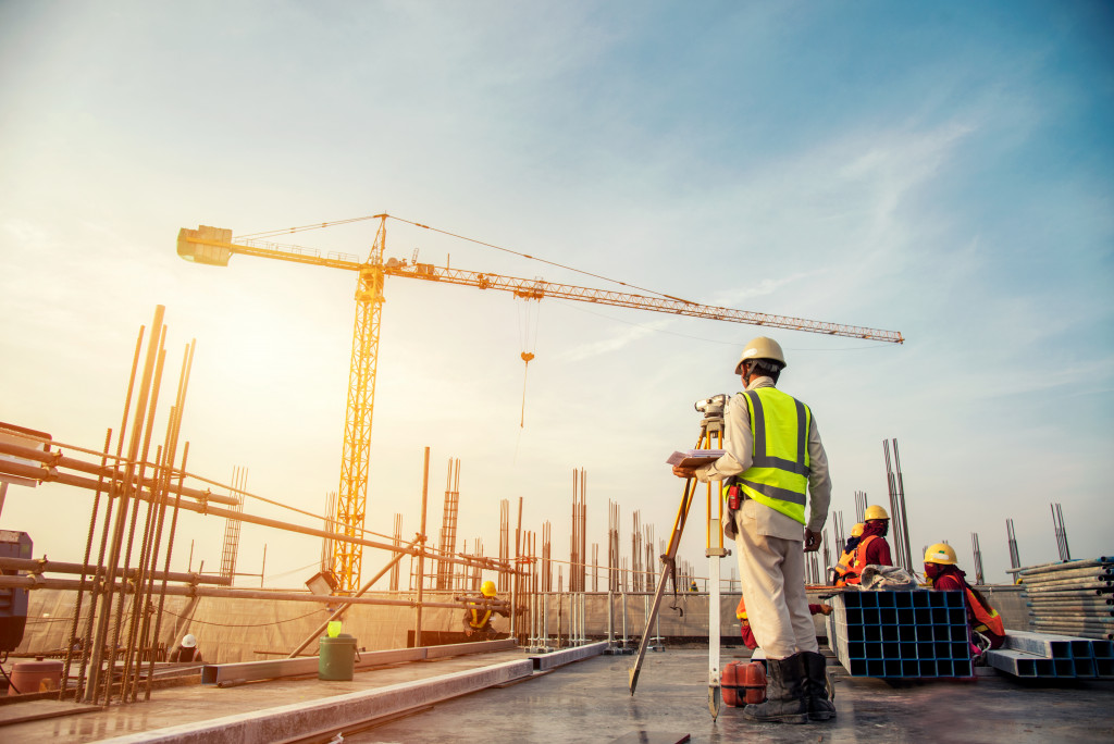 workers surveying the land with large tower crane overhead in the sunset