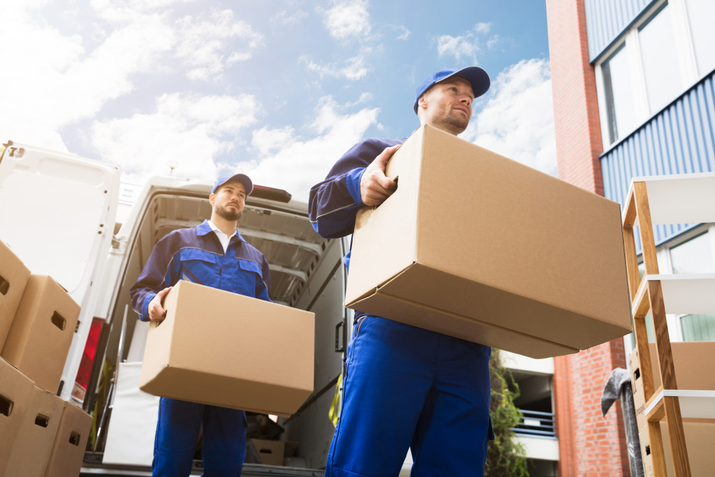 two men carrying boxes unloading 