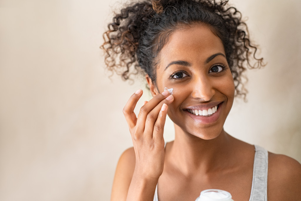 woman doing skin care applying facial moisturizer