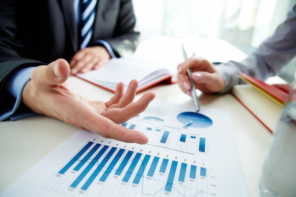 business people discussing and pointing at papers showing graphs and charts about business