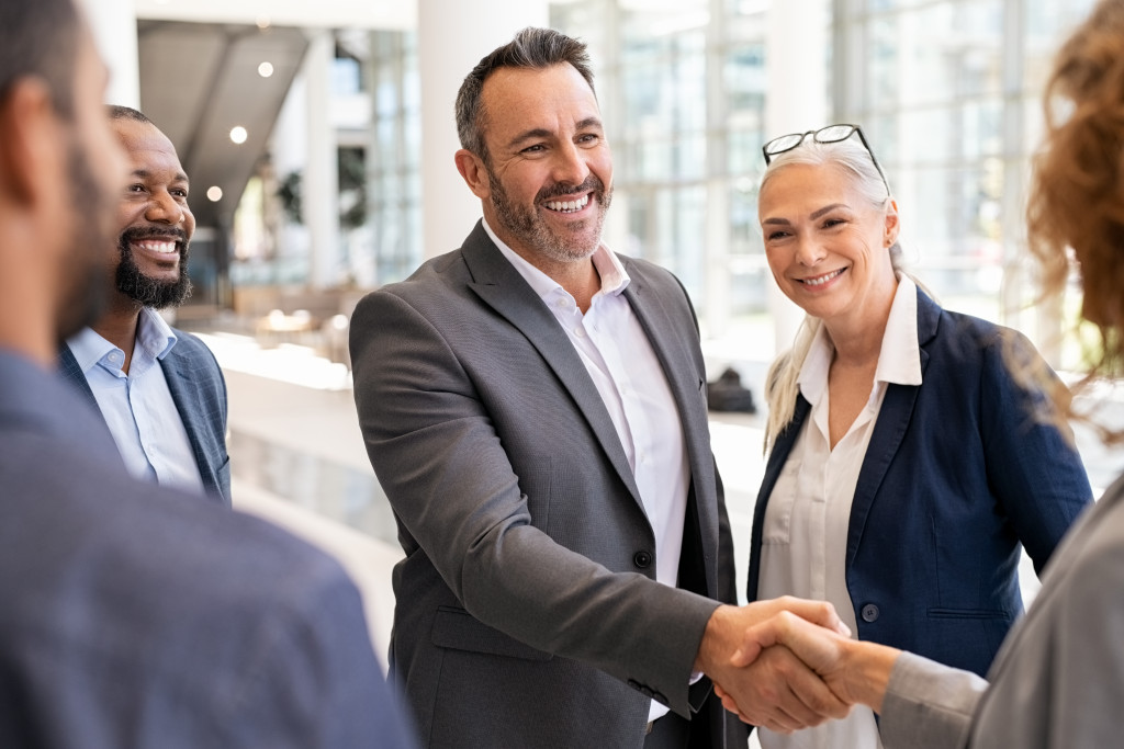 businessman smiling while shaking hands with a female business owner in a networking event