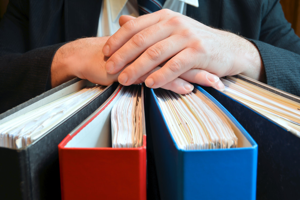 A businessman holding several audit folders