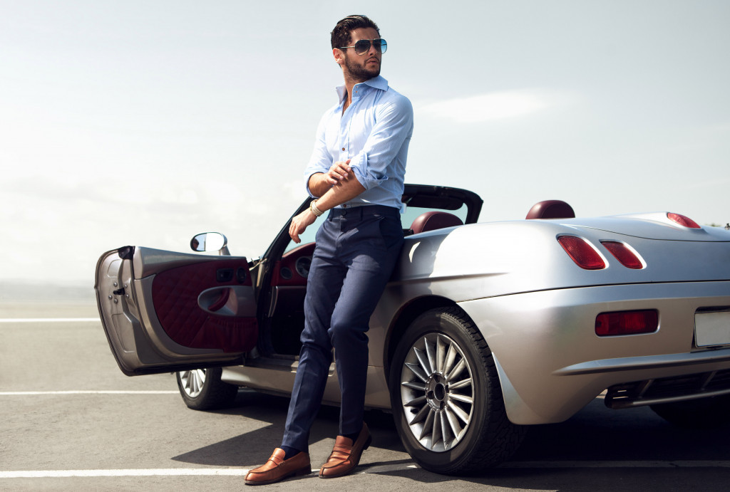 a handsome businessman beside his luxury car