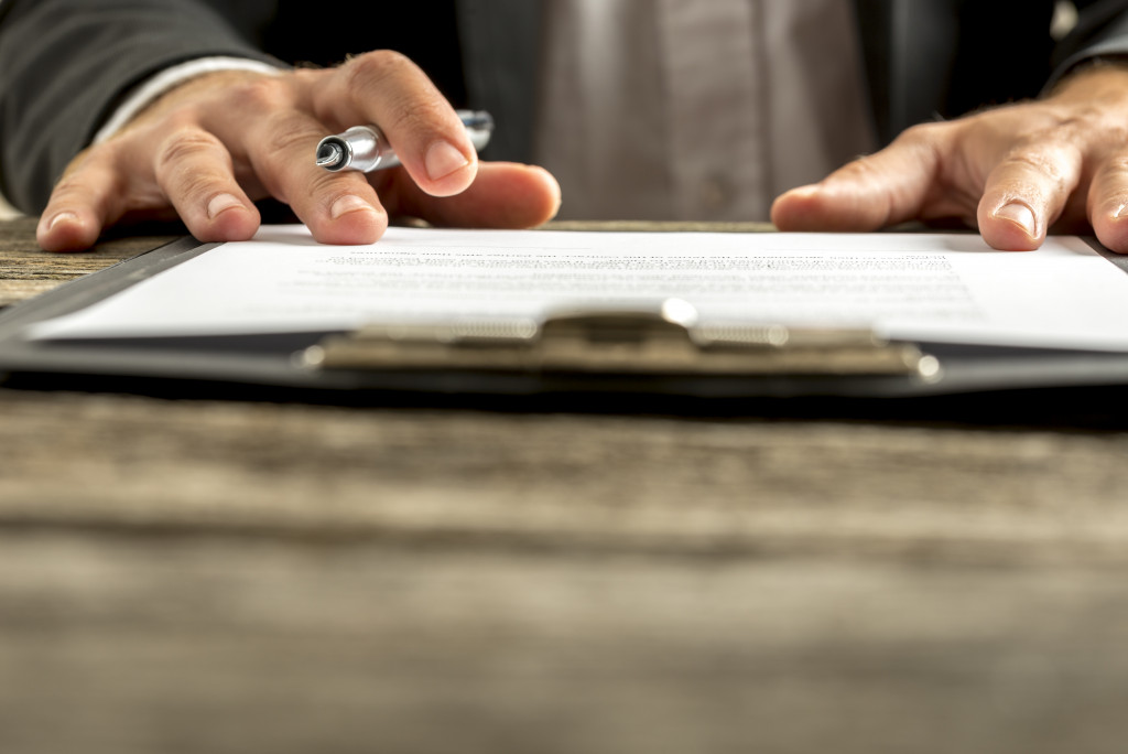 man about to sign a document in a clipboard