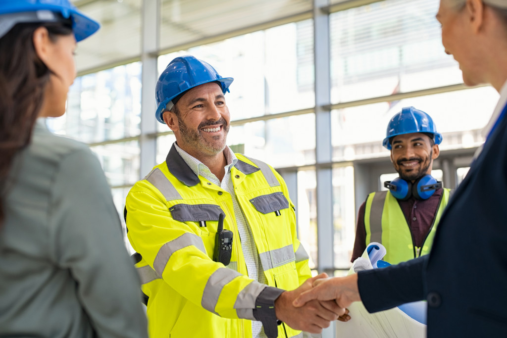 Engineer shaking the hands of a businesswoman at a construction site.